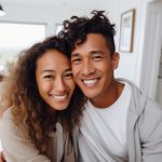 Brown couple with white teeth smile in our their home
